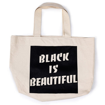 A black and beige cotton tote bag with 'BLACK IS BEAUTIFUL' text printed in bold letters on the side.